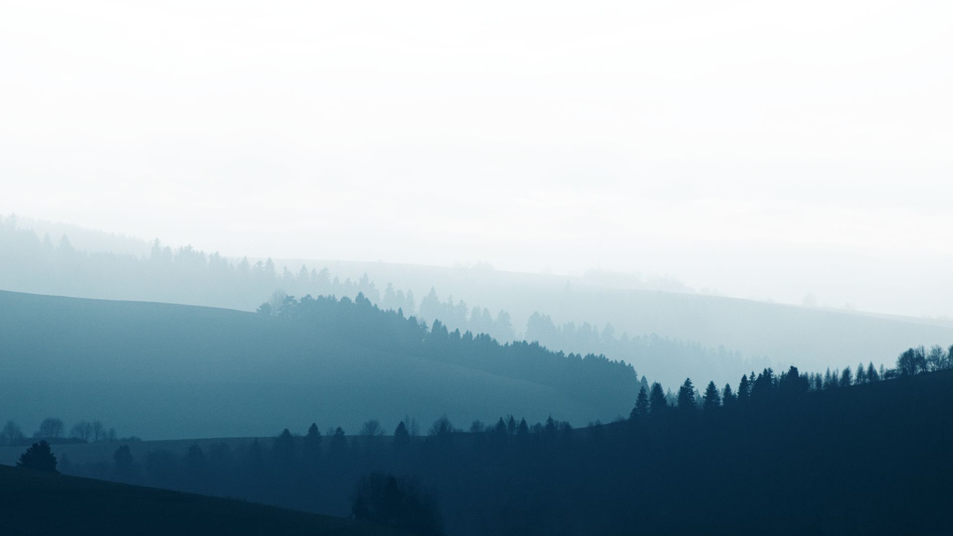 Layered blue mountain ridges fading into morning fog