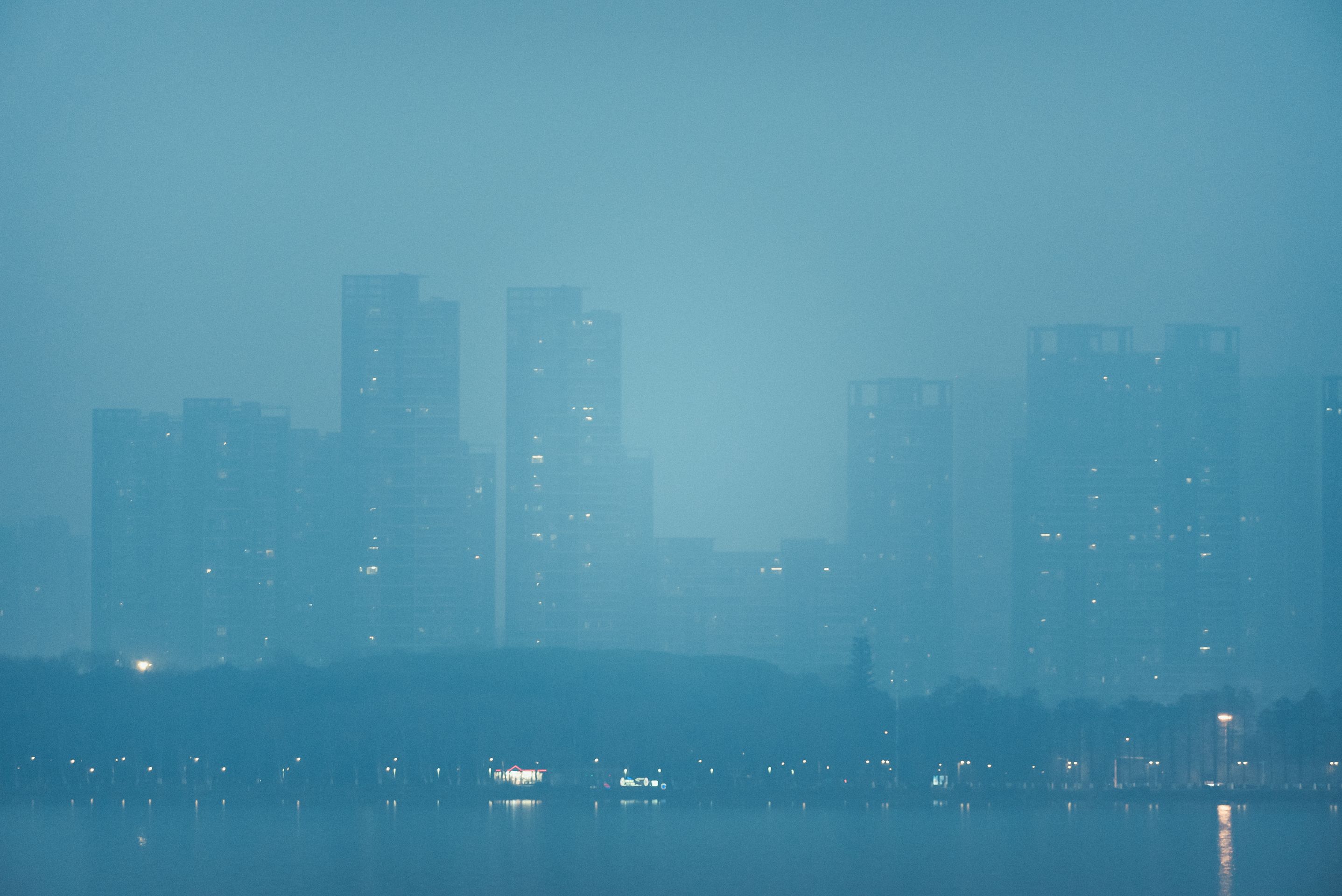 Hazy blue city skyline at dusk, reflected on the water